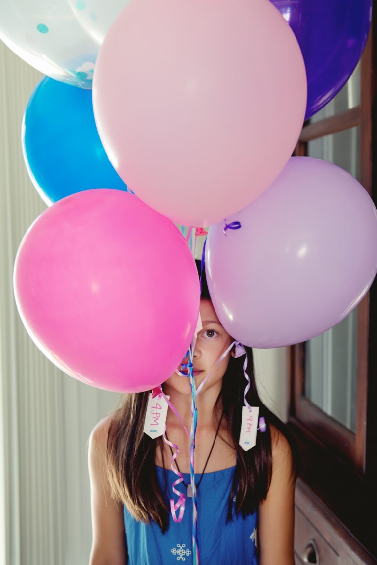 girl hides behind balloons